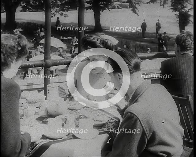A Close up of Two Women and a Man Having Food and Drink on the Roof Terrace at  the Tea..., 1939. Creator: British Pathe Ltd.