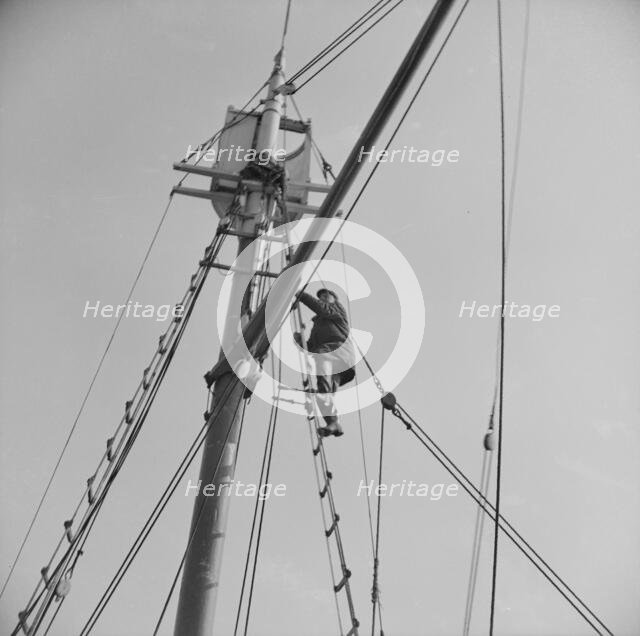 Frank Mineo, owner of the Alden, climbs to the crow's nest..., Gloucester, Massachusetts, 1943. Creator: Gordon Parks.