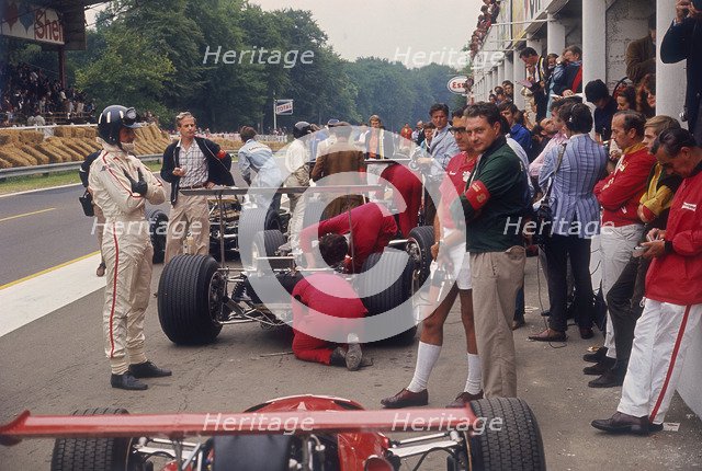 Graham Hill watches Mechanics working on a car, French Grand Prix, Rouen, 1968. Artist: Unknown