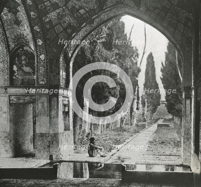 Reproduction of print showing Garden at Fin-Nahe¯, Kashan, Iran. Man seated under arch , c1920. Creator: Frances Benjamin Johnston.