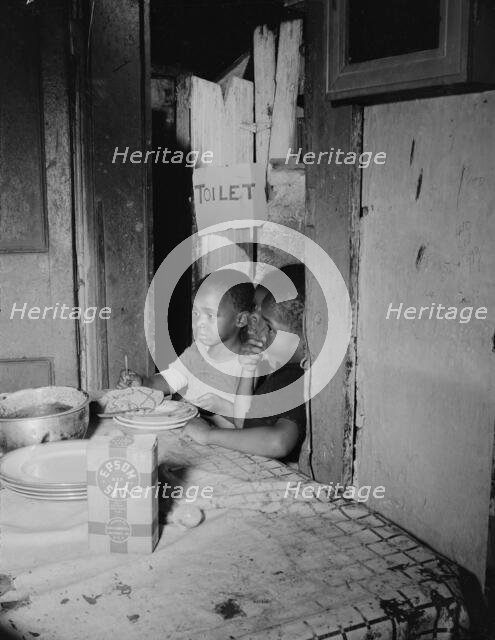 Three children waiting in the kitchen while their mother prepares the..., Washington, D.C, 1942. Creator: Gordon Parks.