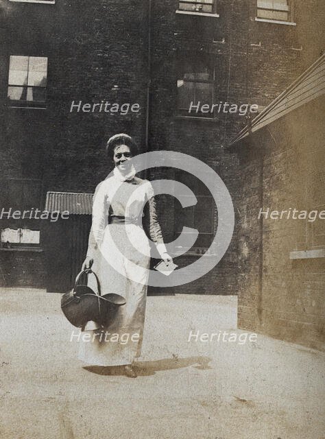 St Bartholomew's Hospital, London: a smiling nurse carrying a coal scuttle, c1890. Creator: Unknown.