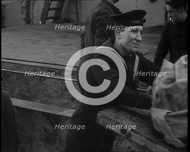Several Male Crew, Including One from the Royal Navy, Inspecting the Cargo of a Large Vessel, 1939. Creator: British Pathe Ltd.