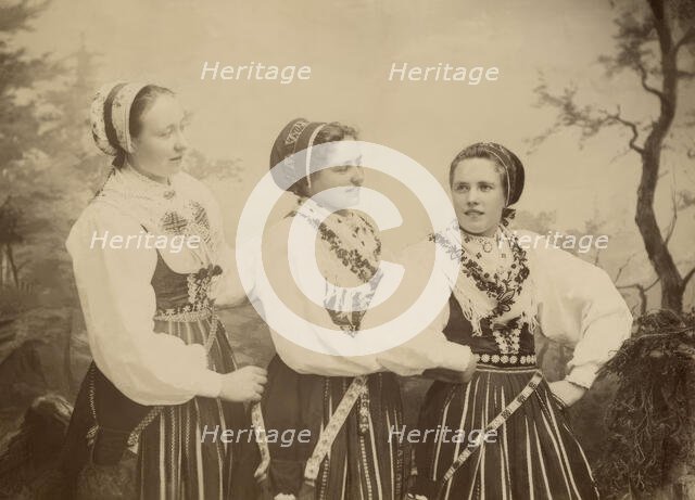 Three young women dressed in costumes from Leksand, Dalarna, 1886-1920. Creator: Helene Edlund.