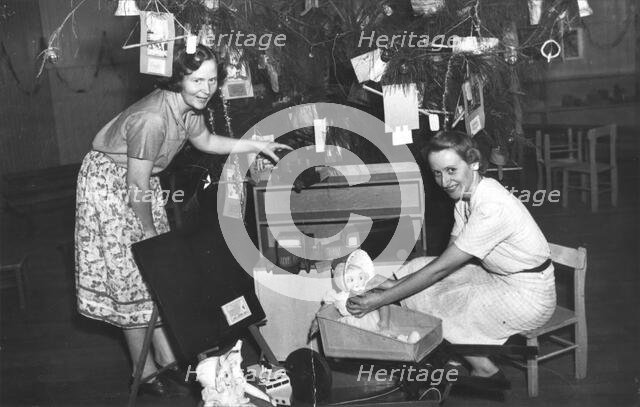 Brisbane Kindergarten Teachers College students/staff with presents and the Christmas tree, 1955. Creator: Unknown.