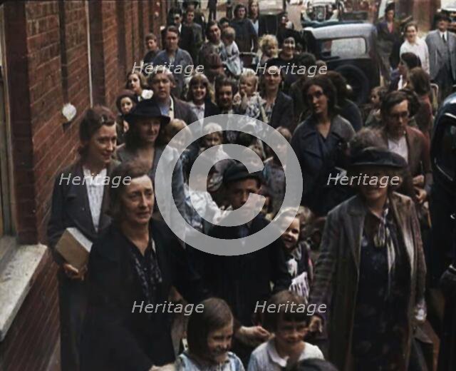 British Women and Child Evacuees Walking Along the Pavement of a Residential Street Next..., 1939. Creator: British Pathe Ltd.