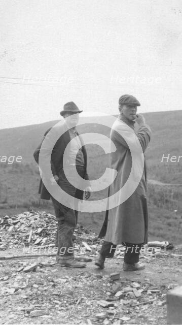 Two men standing near a small pile of rubble, in a field, between c1900 and 1916. Creator: Unknown.