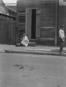 Woman sitting on steps holding a basket, New Orleans, between 1920 and 1926. Creator: Arnold Genthe.