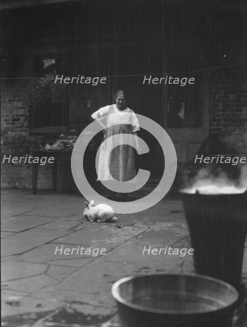Woman and rabbit in a courtyard, New Orleans, between 1920 and 1926. Creator: Arnold Genthe.