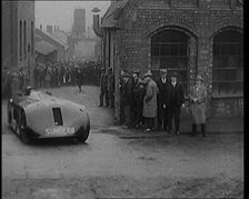 Sir Henry Segrave AKA Major Segrave's Driving  'Sunbeam' Out of a Factory Watched By a..., 1927. Creator: British Pathe Ltd.