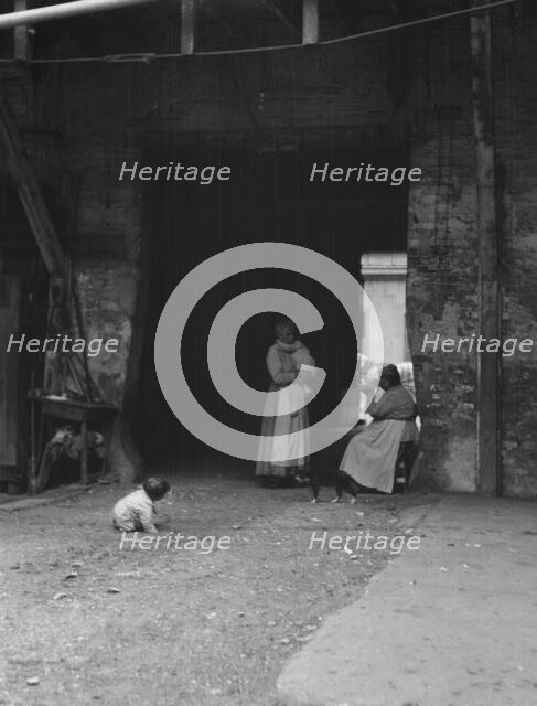 Women and children in a courtyard, New Orleans, between 1920 and 1926. Creator: Arnold Genthe.