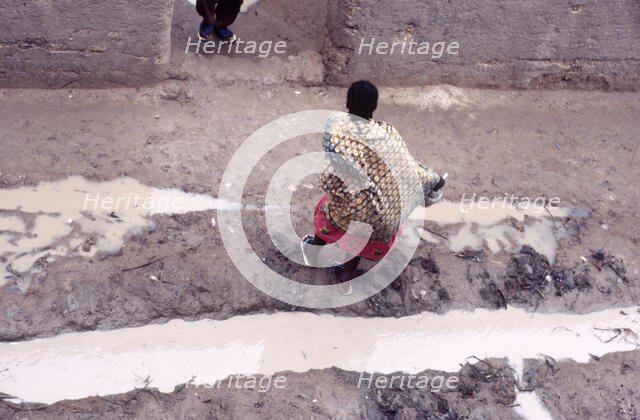 Woman in muddy street, Mopti, Mali, 1990. Creator: Amanda Waite.