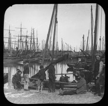 Men and boys with sailing boats in port, unknown location, c1900s. Creator: Robert Augustus Henry L'Estrange.