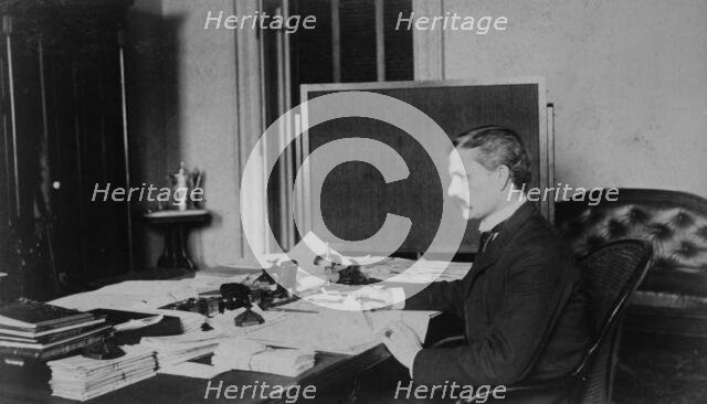 Dr. Miller, Treasury Department employee, half-length portrait, seated at..., between 1884 and 1930. Creator: Frances Benjamin Johnston.