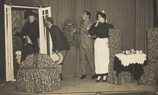 Amateur actors, one in drag, perform a scene on stage, [between 1910 and 1919?]. Creator: Unknown.