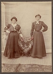 Two women standing at a table holding flowers, about 1875. Creator: Unknown.