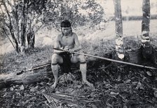 Sarawak: a Kenyah worker tying a spearhead to a blowpipe, c1900. Creator: Unknown.