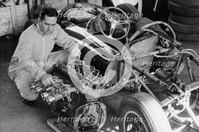 Jack Brabham inspecting the engine of a car. Artist: Unknown
