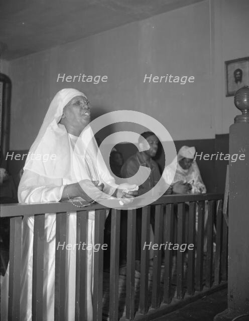 A disciple of the St. Martin's Spiritual Church praying before the altar..., Washington, D.C., 1942. Creator: Gordon Parks.