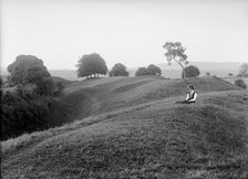 A woman sitting on the external bank at Avebury, Wiltshire, 1908. Artist: Harold St George Gray