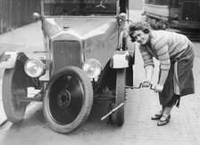 Ivy Cummings changing a tyre on a 1925 Singer 10/26, London, c1925. Artist: Unknown