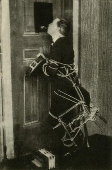 John Nevil Maskelyne performs a 'spirit cabinet illusion', c1910. Creator: Unknown.
