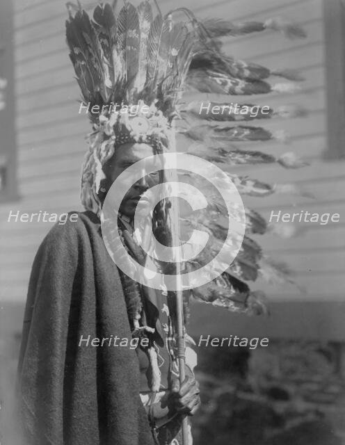 Piegan war-bonnet and coup-stick, c1910. Creator: Edward Sheriff Curtis.