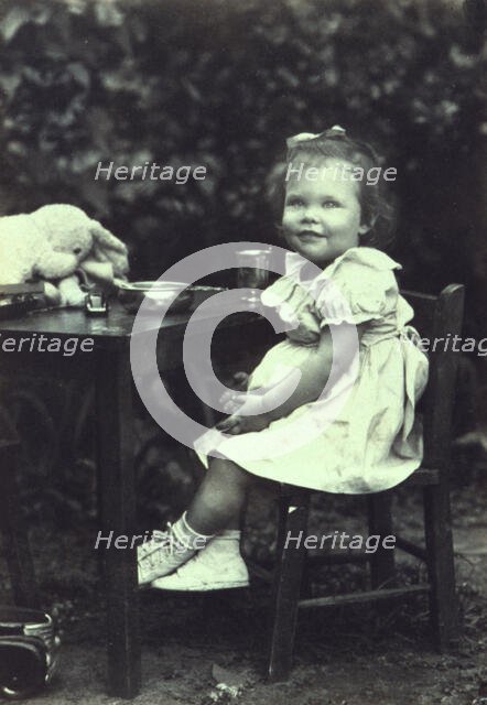 Portrait of a young girl seated at an outdoor table, facing front, between 1940 and 1950. Creator: Joseph Woodson Whitesell.