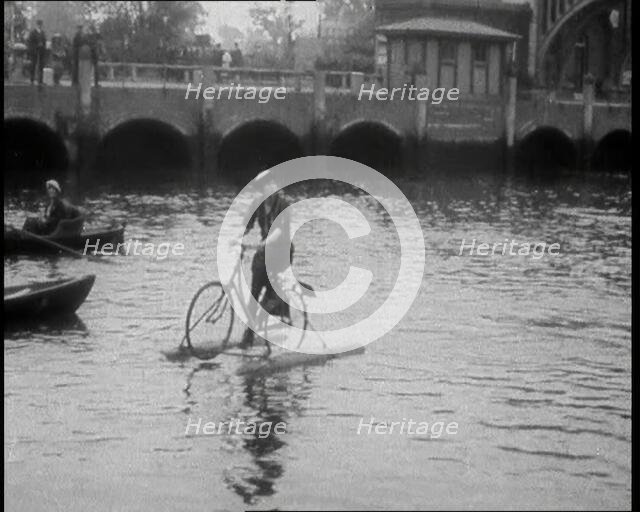 Woman Riding Along a River on a Floating Bicycle Contraption, 1920. Creator: British Pathe Ltd.
