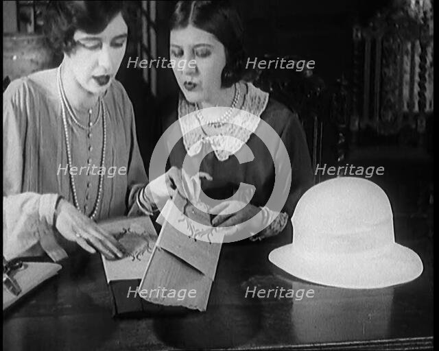 Two Female Civilians Cutting  Sheets of Paper to Decorate a Hat, 1920. Creator: British Pathe Ltd.