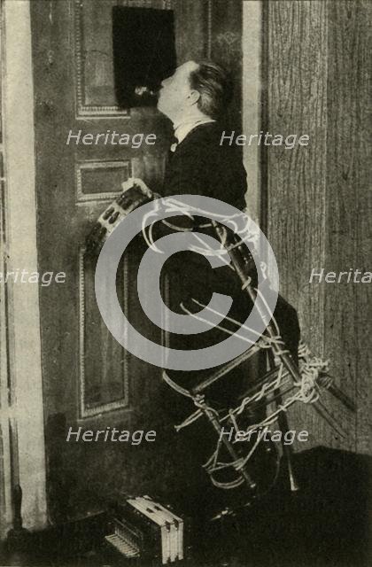 John Nevil Maskelyne performs a 'spirit cabinet illusion', c1910. Creator: Unknown.