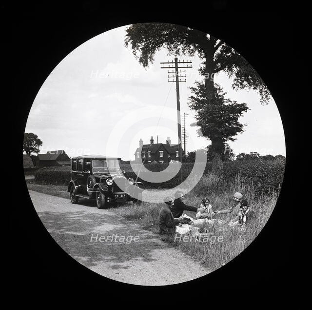 A group of women and girls having a picnic near a parked car at the side of a road..., 1920s-1930s. Creator: Norman Kingsley Harrison.