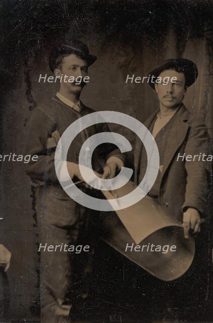 Two Tinsmiths Cutting a Curled Sheet of Metal, 1880s. Creator: Unknown.