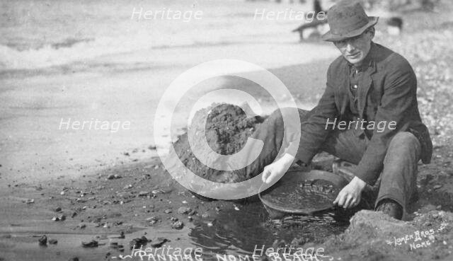 Man panning gold on Nome Beach, between c1900 and c1930. Creator: Lomen Brothers.
