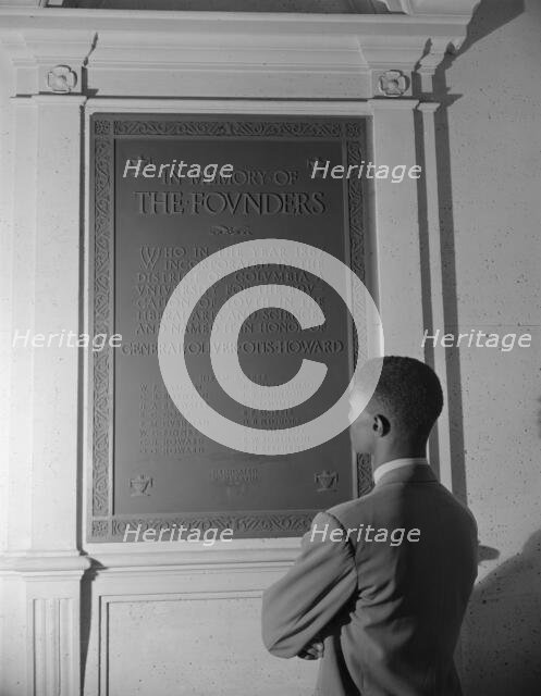 Student reading bronze plaque in library of Howard University, Washington, D.C., 1942. Creator: Gordon Parks.