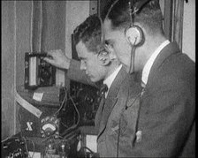 Two Men Wearing Headphones and Calibrating Wireless Equipment, 1922. Creator: British Pathe Ltd.