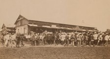 Crowds of people in front of buildings at the marketplace in the center of town..., (1899?). Creator: Eleanor Lord Pray.