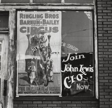 Barber shop window [with circus poster] in Birmingham, Alabama,  1937-01 - 1937-02. Creator: Arthur Rothstein.