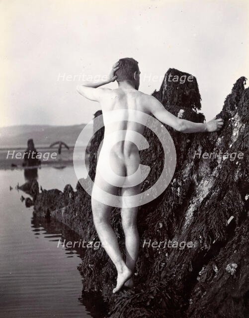 A man posing naked, with his back to the camera, standing on a rocky outcrop, c1900. Creator: Unknown.