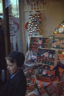 Boy beside store window display of Christmas ornaments, between 1941 and 1942. Creator: Unknown.