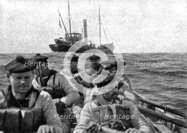 At Sea: The coastguard: boarding crew going aboard a suspect trawler..., 1917. Creator: Unknown.