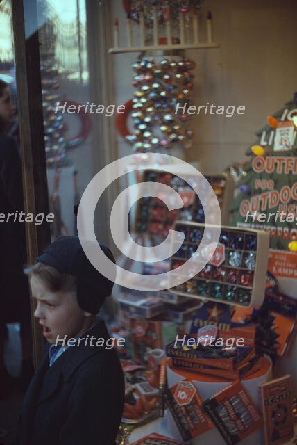 Boy beside store window display of Christmas ornaments, between 1941 and 1942. Creator: Unknown.