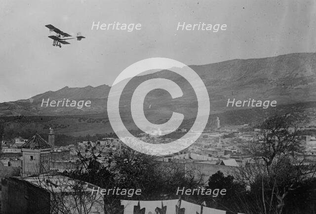 Breguet biplane, type 1910, flying over a town, possibly in Morocco, between c1910 and c1915. Creator: Bain News Service.