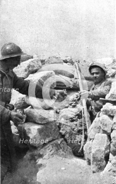 Life in the trenches in Champagne; A lookout 'teased' by the enemy is passed hand grenades, 1917. Creator: Unknown.