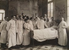 Medical staff standing round a woman patient in bed in a hospital ward, c1910. Creator: Freres Seeberger.