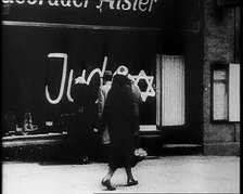 Civilians Looking at  Shop Window with Graffiti Reading: ‘Juden’ on it, 1933. Creator: British Pathe Ltd.