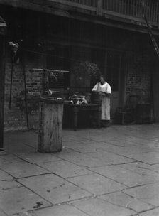Woman working in a courtyard, New Orleans, between 1920 and 1926. Creator: Arnold Genthe.