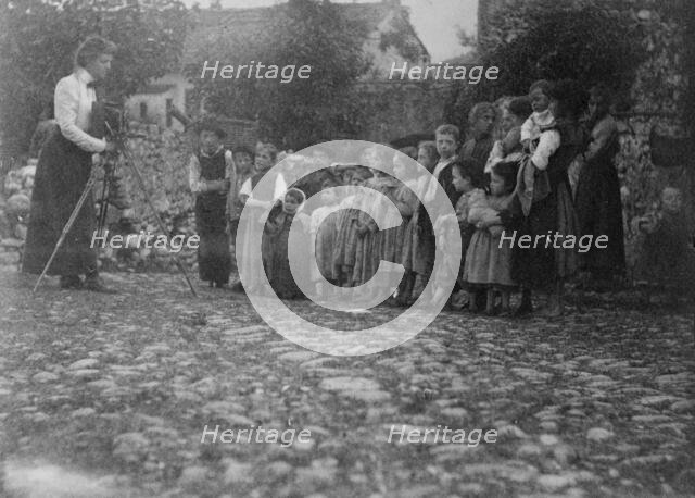 Frances Benjamin Johnston photographing a group of people, mostly children, in Europe, 1900. Creator: Unknown.