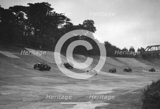 Cars racing on the banking at a JCC Members Day, Brooklands. Artist: Bill Brunell.