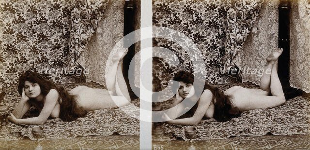 A young woman posing naked in a photographic studio, lying on her front on a piece of..., c1900. Creator: Unknown.